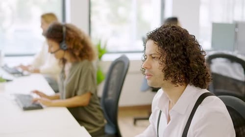 Homem trabalhando com computador em um coworking ao lado de colegas