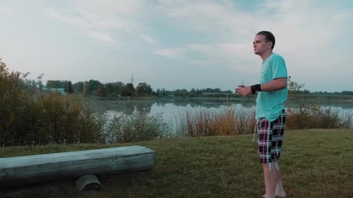 A Young Guy Is Boxing Training In Nature Behind A Lake Or A Quarry