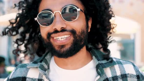 Smiling Young Adult with Curly Hair and Beard