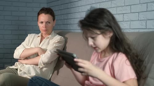 Woman Watches Child Playing on Tablet on Couch