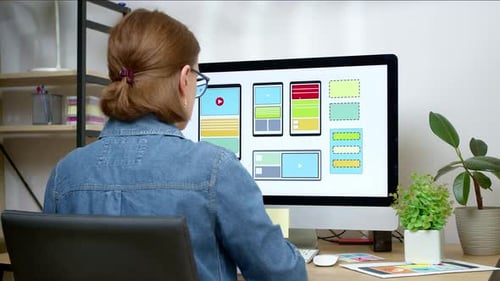 A UI designer develops a web site interface using a computer.