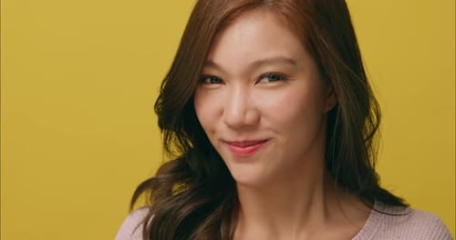 Smiling Woman with Finger to Lips on Yellow