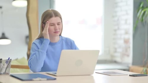 Young Woman with Headache Uses Laptop at Desk