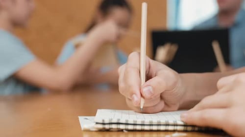 Nahaufnahme der Studentenhand, die eine Notiz macht, während das Mädchen eine Frage stellt. Erbauung
