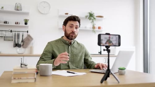 Male Blogger Using Smartphone and Tripod for Live Streaming