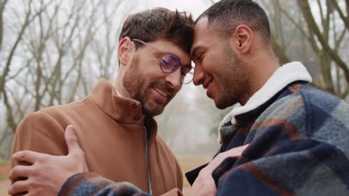 Happy Homosexual Couple in Overcoats Standing Opposite Each Other in Park Outdoor