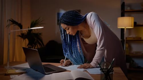 Young Adult Studying at Desk with Laptop at Night