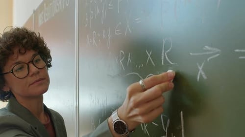 Math Teacher Writing Equations on Chalkboard