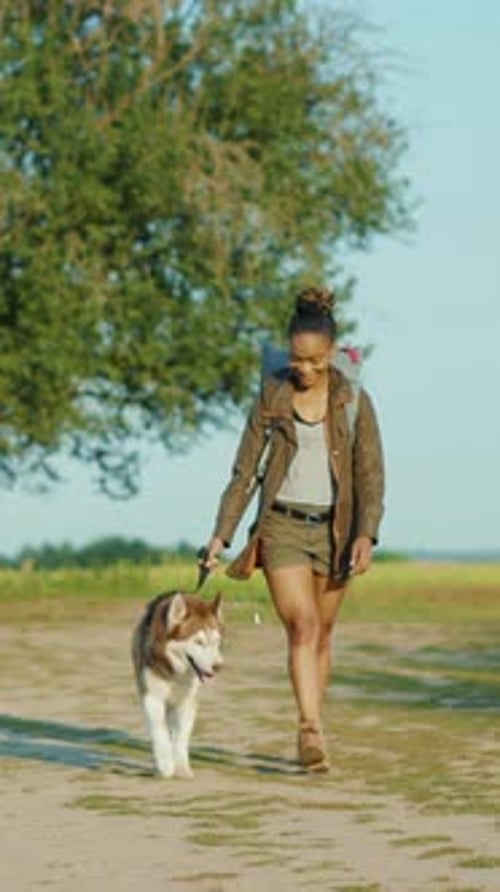 A Woman Takes a Leisurely Walk with Her Dog Through the Beautiful Natural Landscape