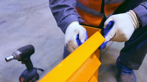 Closeup Employee Twists Screw on Metal Construction
