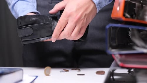 Businessman Dropping Last Coins From Empty Wallet at Office Desk