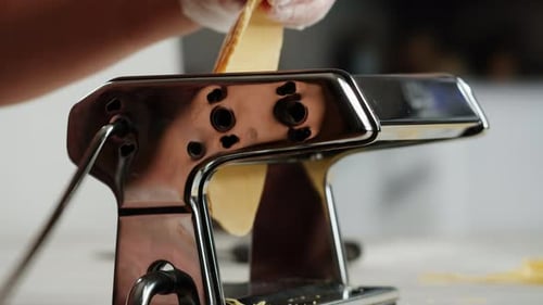 Woman Using Pasta Machine to Make Fresh Pasta Dough in the Kitchen Cooking in Italian Restaurant