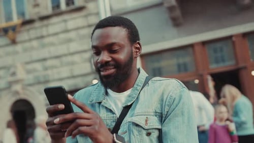 Portrait Young African Amerian Man Stand the Street and Uses Phone Camera Moving Around Happy Smile