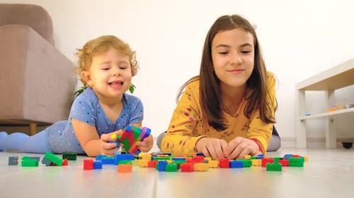 Two Girls Lying on Floor Playing with Building Blocks