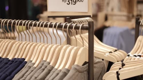 Closeup of Hangers with Clothes in a Store Clothes for Sale Hang on Wooden Hangers a New Collection