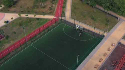 Amateur Boys Have Fun with a Ball on an Artificial Soccer Court Pitch