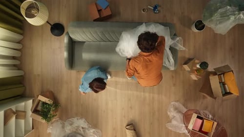 Top View of Living Room Couple Taking Off the Film From Sofa in New Apartment Sitting Tired Talking
