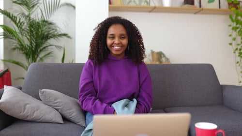 Woman Talks to Laptop on Couch at Home