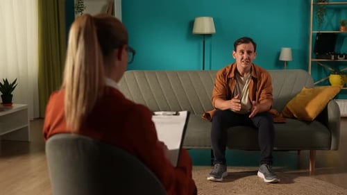 Female Psychologist Counseling a Man and Giving Recommendations for Mental Health Therapy Back View