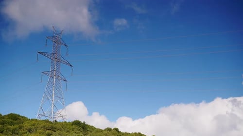 Electrical Transmission Tower on Green Hill Under Blue Sky