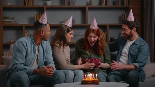 Friends celebrate birthday indoors with cake and gifts