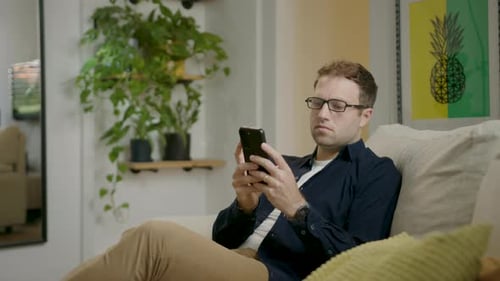 Man Using Mobile Phone Reclined on Couch Indoors