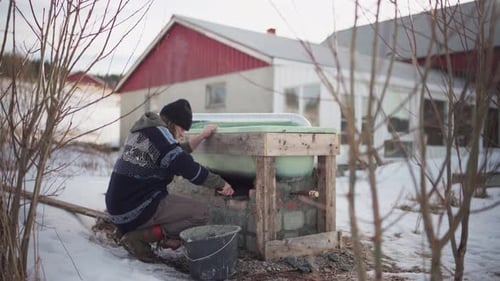 Adult Builds Tub Support in Snowy Winter Landscape