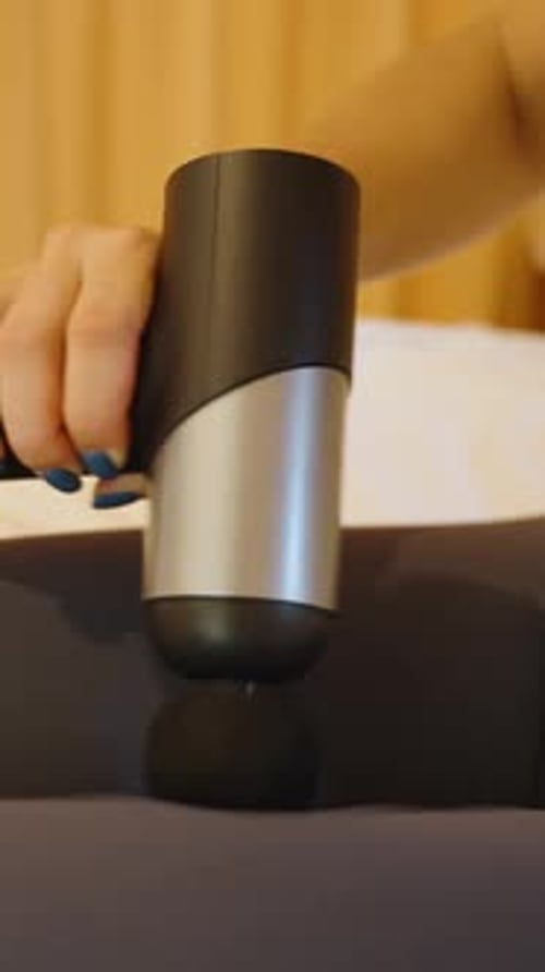 Vertical video. Close up of massage gun applied to knee area, muscle therapy concept