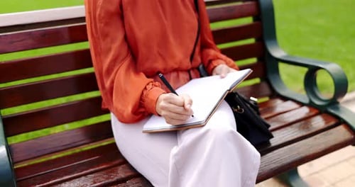 Park, bench and a woman writing in a notebook, diary or journal while outdoor in a garden to relax