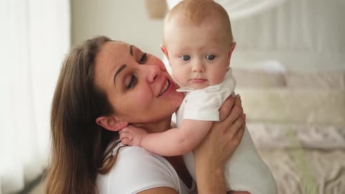 Loving Mother Cuddles Adorable Baby at Home