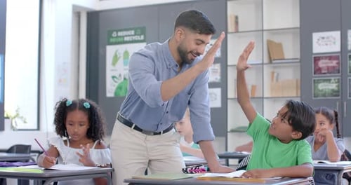 Teacher assists biracial boy and girl in a classroom at school