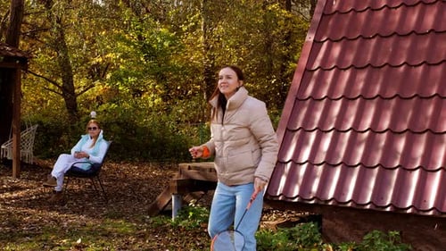 Women Relax in Nature in Autumn Playing Badminton at a Forest House