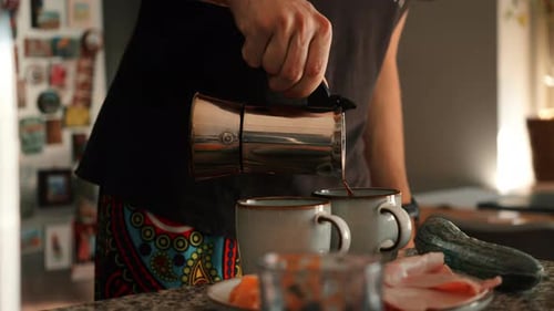 Man Pours Coffee into Mugs in Kitchen
