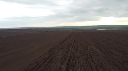 Blue tractor with yellow seeder working on the field in Ukraine OA