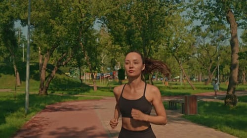 Woman Runs Through Sunny Urban Park