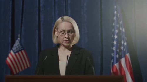 Woman Giving a Speech Behind Podium with Flags