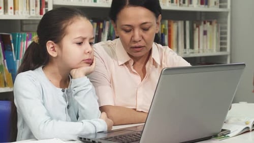 Child Learning with Adult in a Library Using Laptop