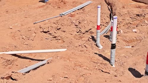 Construction Site with Exposed Plumbing Electrical Conduits During Groundwork Phase