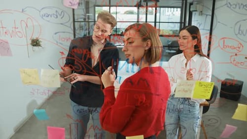 Team Brainstorming Ideas on Glass Whiteboard in Office