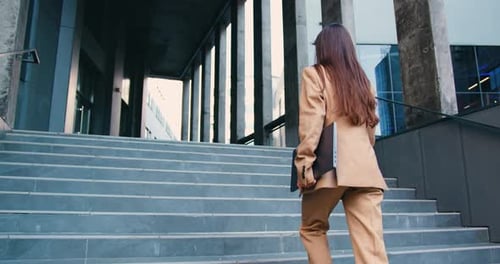 Young Caucasian Businesswoman Came on of an Office Building Walking Up the Stairs and Holding Laptop