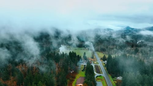 Mountain road with foggy landscapes. Aerial morning foggy road in forest.