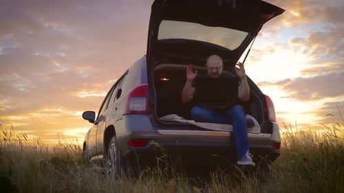 Homem que trabalha remotamente em um laptop acena com as mãos irritadamente, incapaz de lidar com o estresse sentado