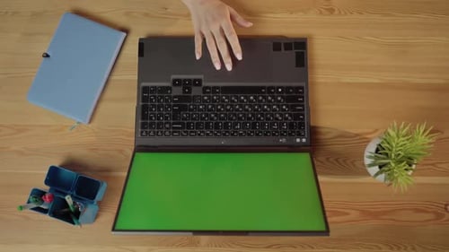 User Hand Interacting with the Touchpad of a Modern Laptop Featuring a Customizable Green Screen