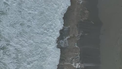 Aerial Video Towering Storm Waves Leave Swirling Foam Designs on the Sandy Beach During a Storm