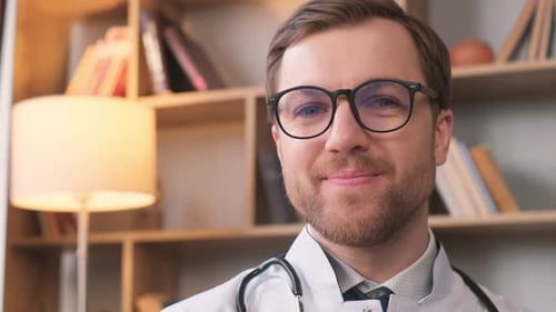 Portrait of a Handsome Young Doctor in a White Coat He is Looking at the Camera and Smiling