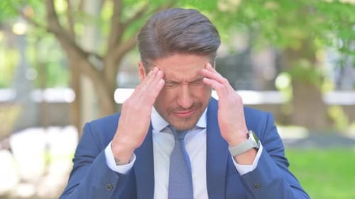Outdoor Portrait of Middle Aged Businessman with Migraine