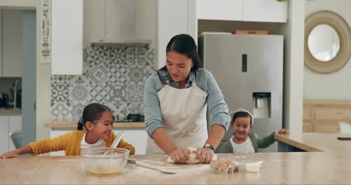 Woman Kneading Dough with Two Young Girls in Kitchen