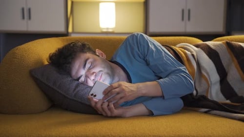 Man with Phone Lies Down on Couch and Sleeps