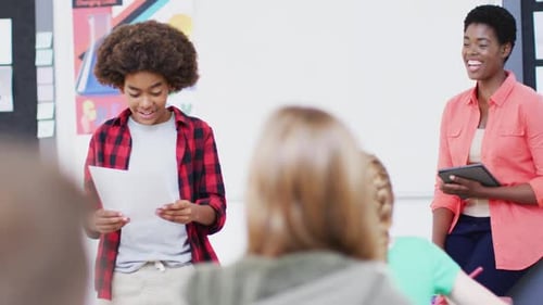 Professeure diversifiée et écolières heureuses à leur pupitre récitant en classe