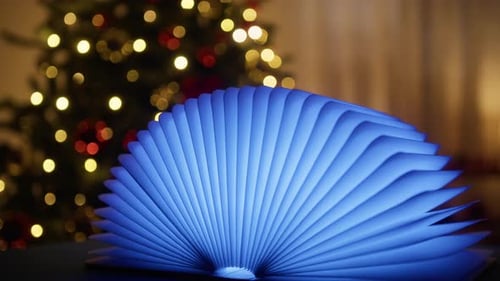 Un livre lumineux pivote sous le sapin de Noël